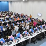 Grupo diverso de colegas participa de uma confraternização em ambiente interno decorado com balões coloridos.