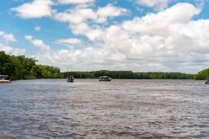 Embarcações navegam por um rio cercado por vegetação no Maranhão, sob céu claro.