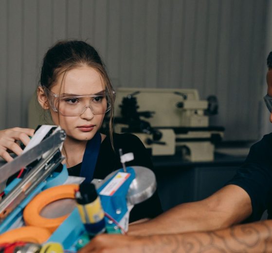Jovens engenheiros colaboram na montagem de um equipamento robótico em uma oficina industrial.