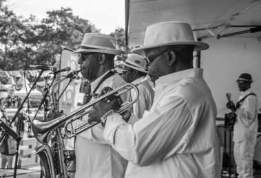 Banda de jazz se apresenta ao ar livre com saxofone e trompete.