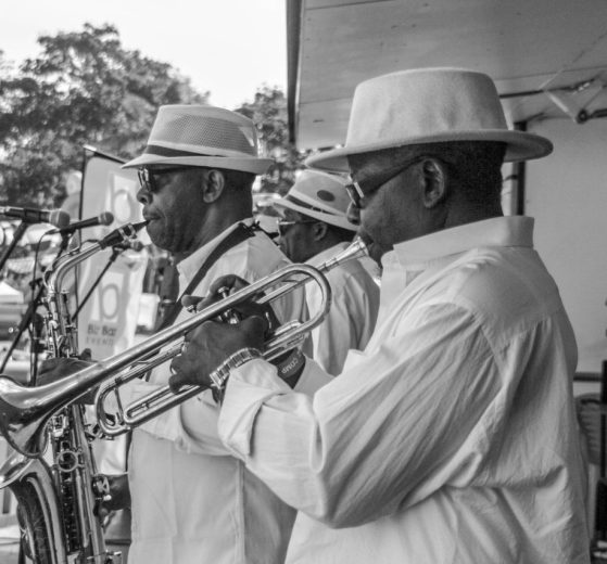 Banda de jazz se apresenta ao ar livre com saxofone e trompete.