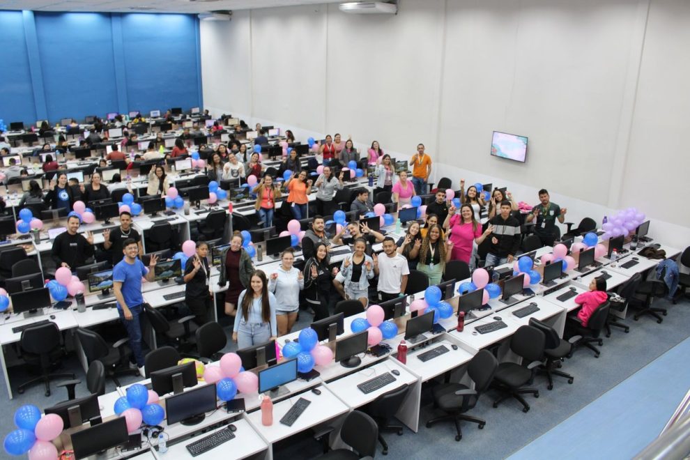 Grupo diverso de colegas participa de uma confraternização em ambiente interno decorado com balões coloridos.