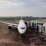 Avião comercial estacionado junto ao terminal de um aeroporto, pronto para o embarque.