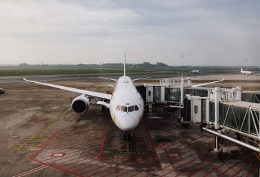 Avião comercial estacionado junto ao terminal de um aeroporto, pronto para o embarque.