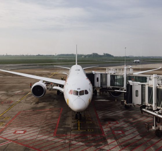 Avião comercial estacionado junto ao terminal de um aeroporto, pronto para o embarque.