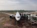 Avião comercial estacionado junto ao terminal de um aeroporto, pronto para o embarque.
