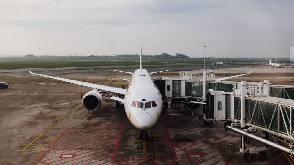 Avião comercial estacionado junto ao terminal de um aeroporto, pronto para o embarque.