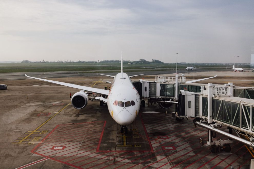 Avião comercial estacionado junto ao terminal de um aeroporto, pronto para o embarque.